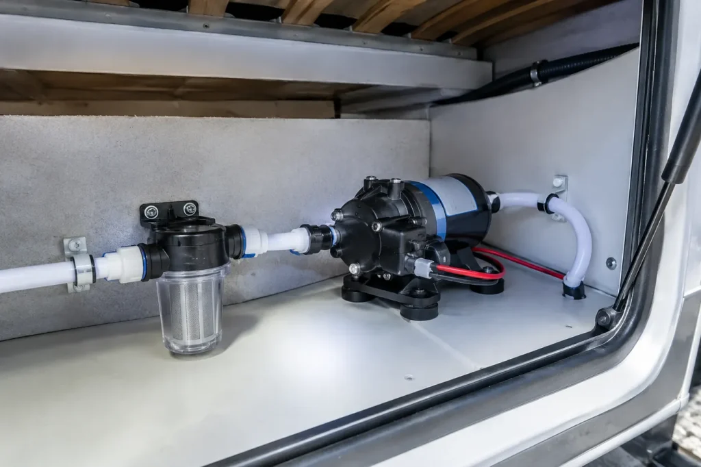 12 volt RV water pump with strainer in a storage bay